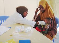 A health worker at an IRC clinic in Somalia examines a baby during our response to the famine in 2011. 