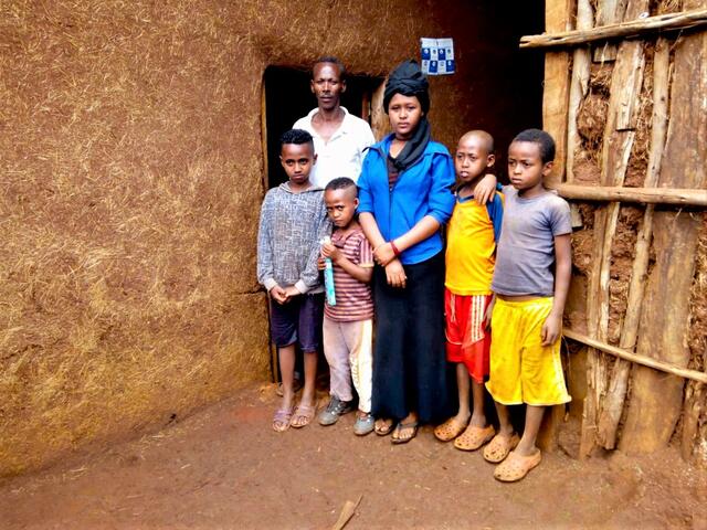 Tadel Chengere, a farmer in Ethiopia, standing with his family outside his home