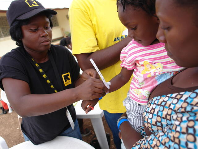 An IRC relief worker assists two young Haitian girls