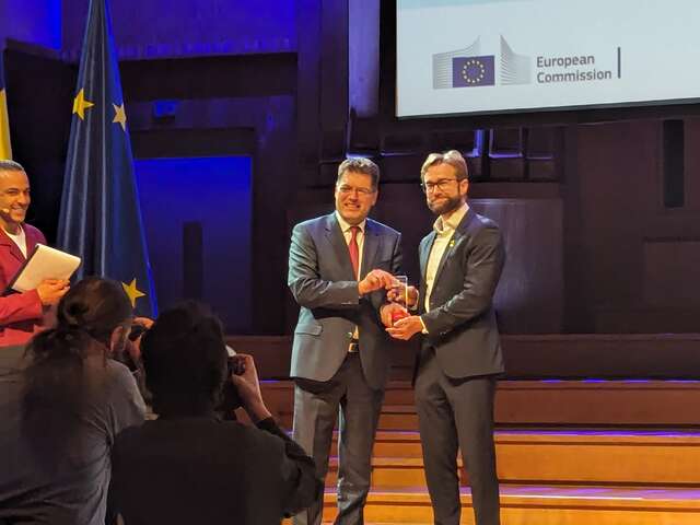 IRC Signpost Director Andre Heller accepting award from EU Commissioner Janez Lenarčič on stage at the 2024 European Humanitarian Forum