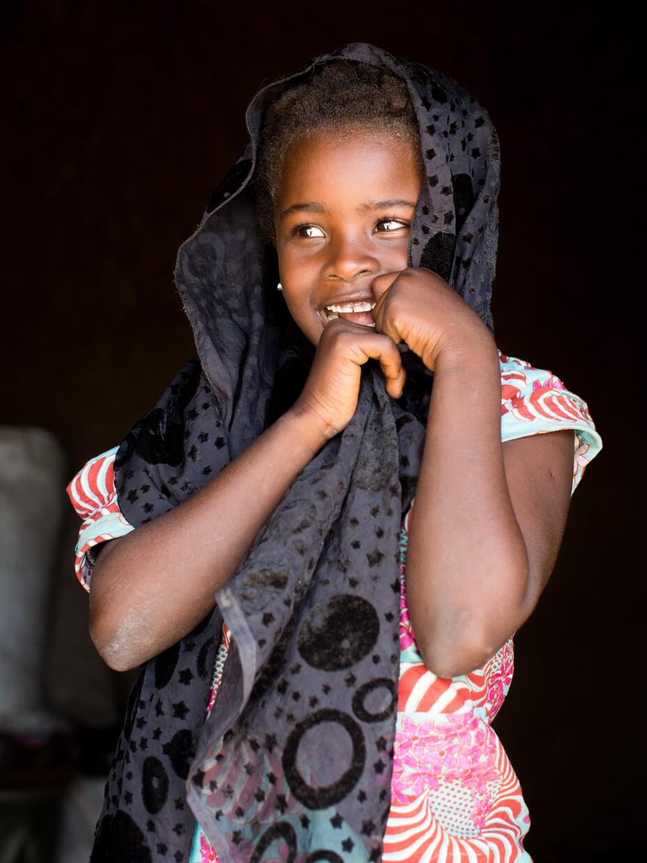 A young girl with headscarf is smiling