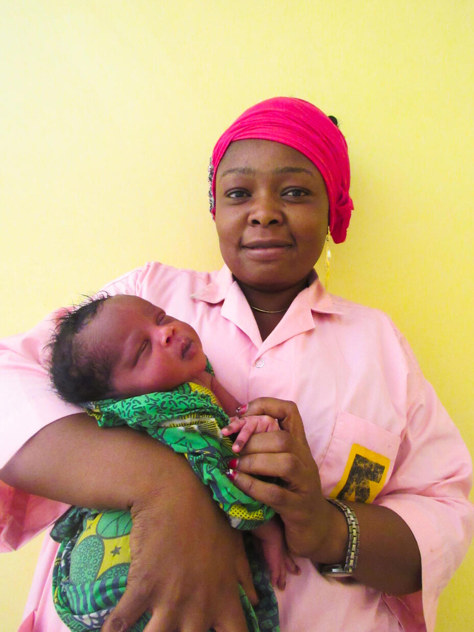 Portrait of Josiane, IRC midwife, holding Khaltouma's baby