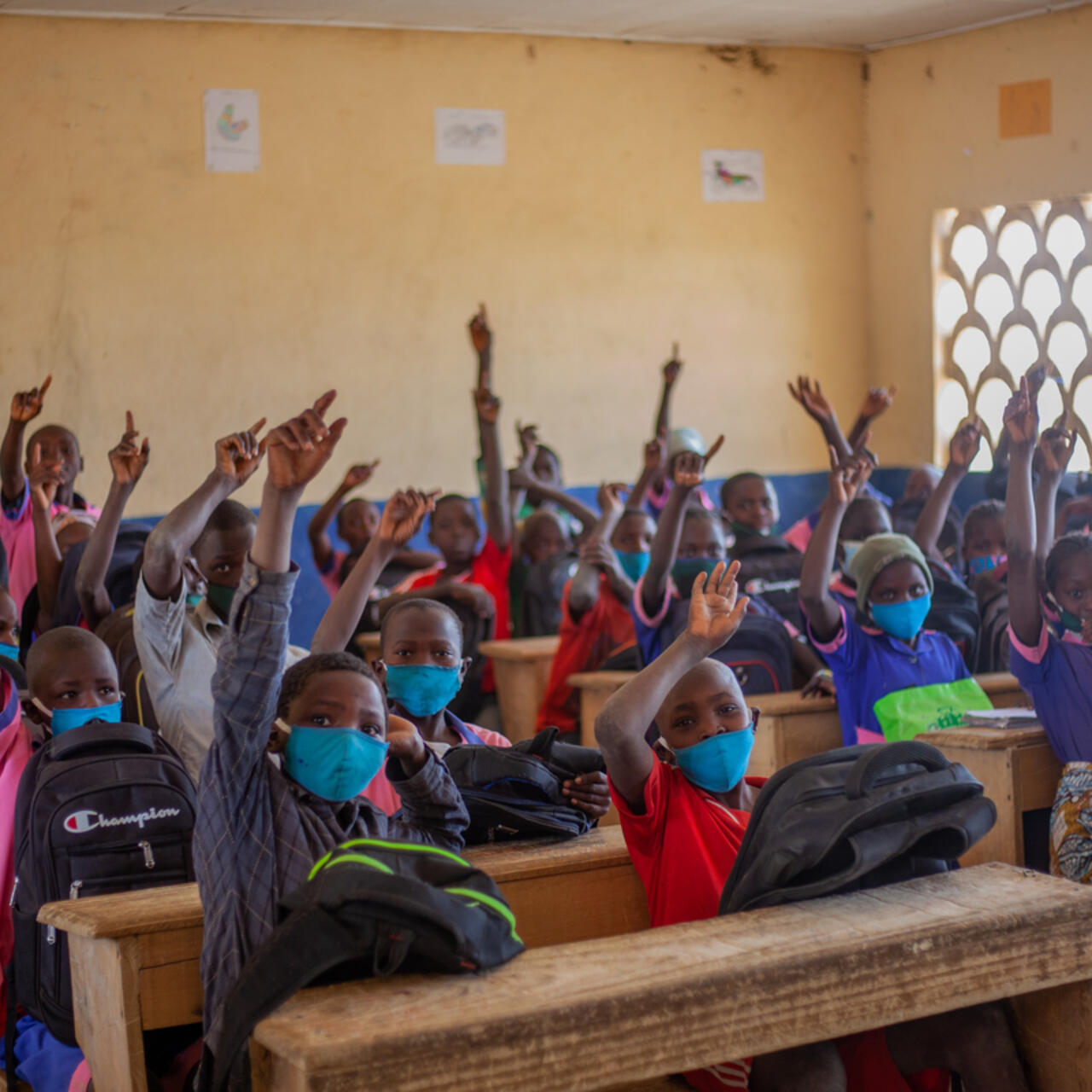 Shot of children in a public school raising hands