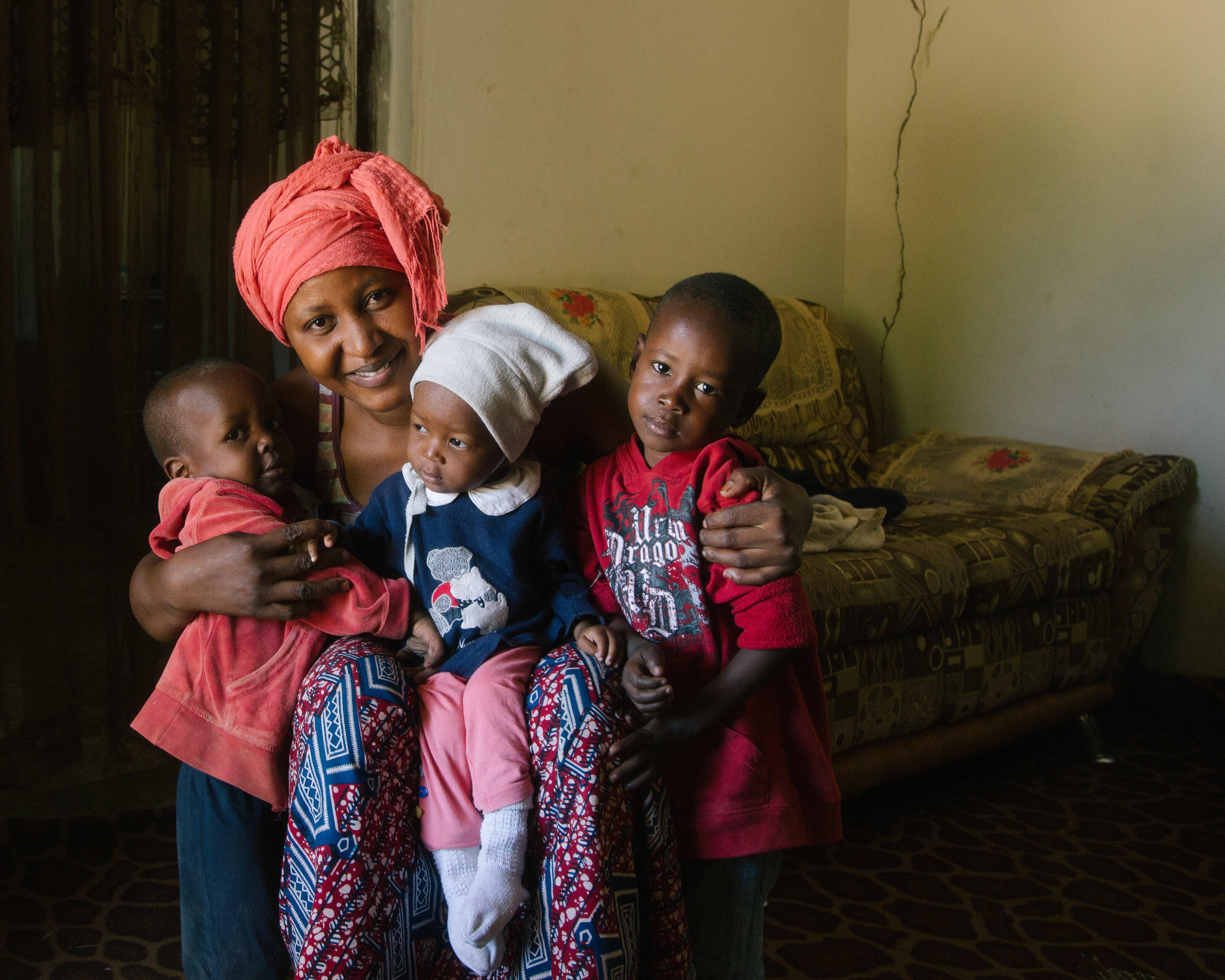 Jafiada sits with her three children on a sofa and smiles