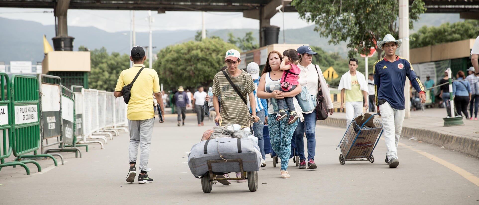 people crossing a border and carrying stuff