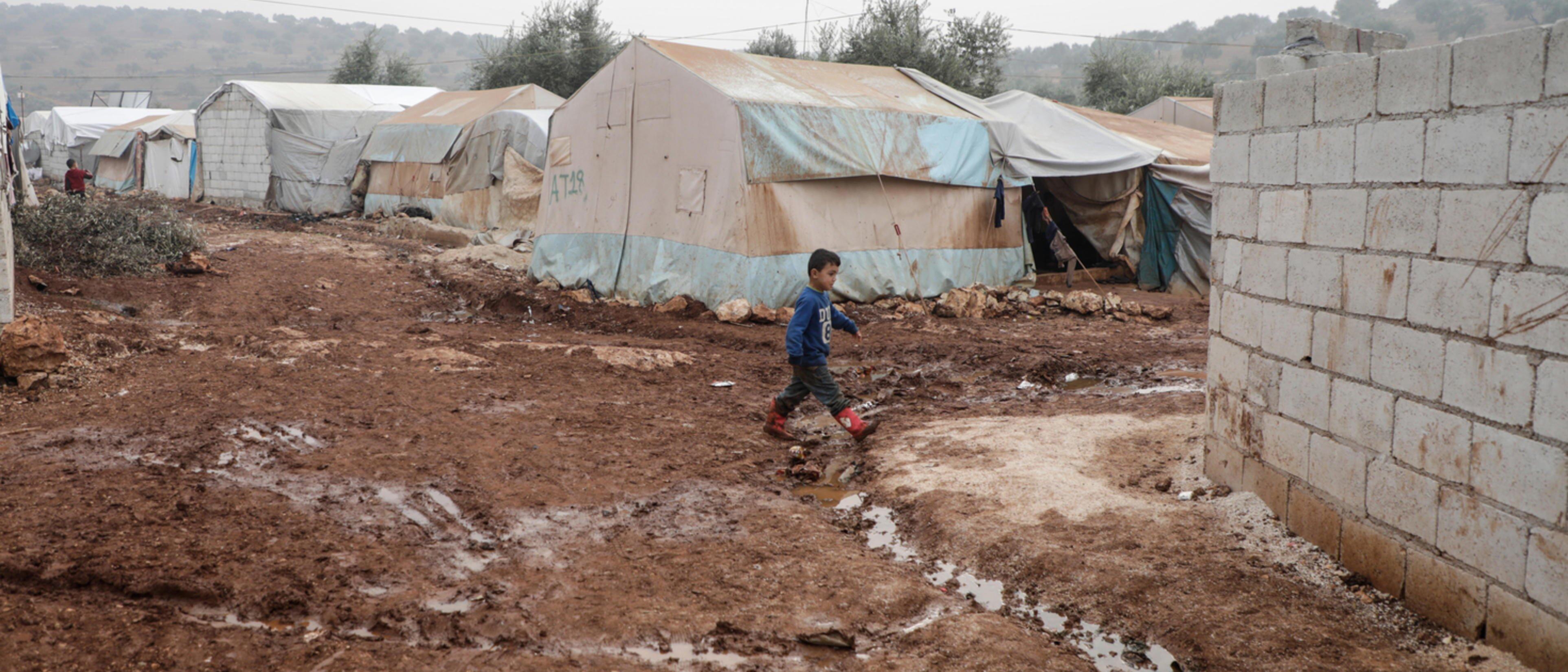 A boy walking through muddy barracks