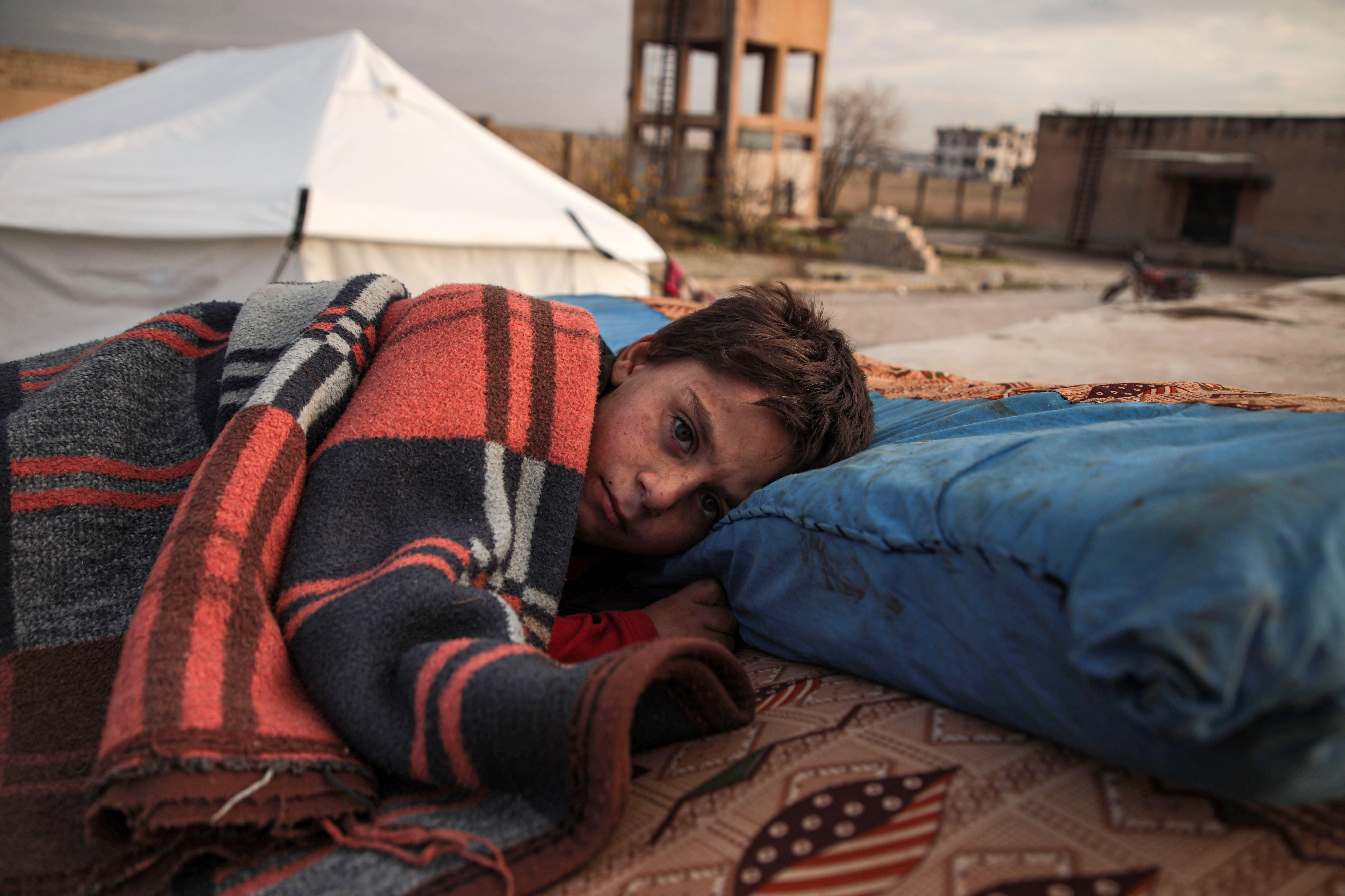 A Syrian child sleeps in the open at a displacement camp near Turkey’s border after fleeing from southern Idlib. 
