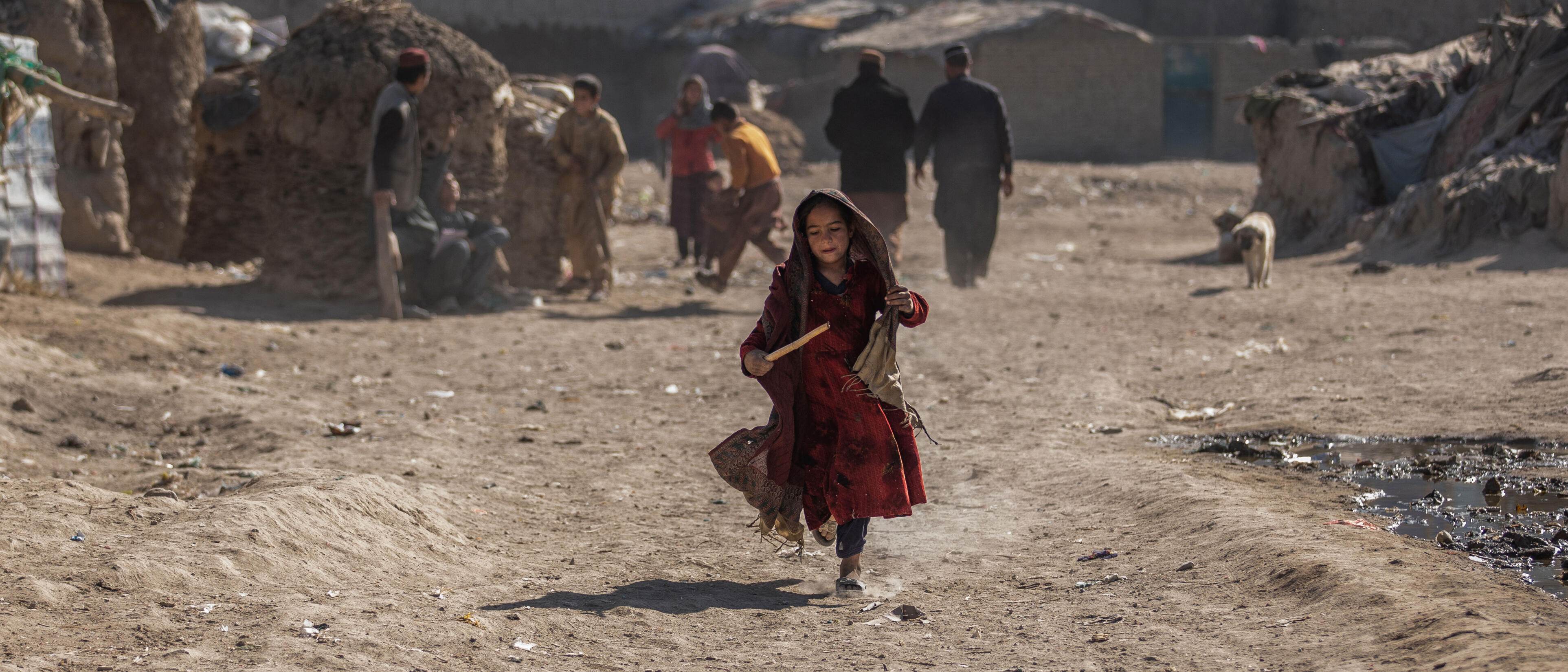 Afghan girl running with stick