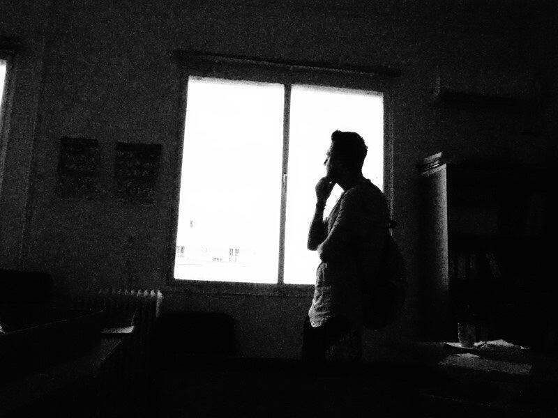 Black and white photo of Ahmad standing against a window looking outside