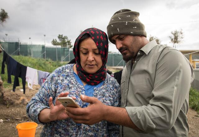 A man and a woman looking in a smartphone