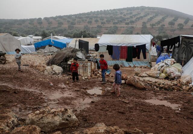Children in front of tents on muddy grounds
