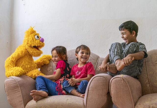Sesame puppets with children on a couch