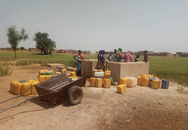 Some people stand around a well to fill fresh water in their jerrycans
