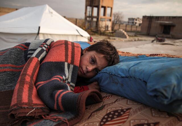 A Syrian child sleeps in the open at a displacement camp near Turkey’s border after fleeing from southern Idlib. 