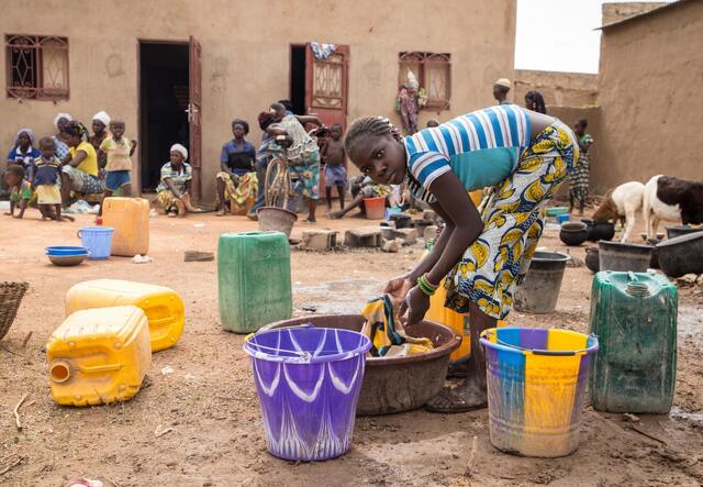 Ein Mädchen wäscht ihre Kleidung vor einer Notunterkunft für Familien, die vor der Gewalt in Burkina Faso fliehen mussten.