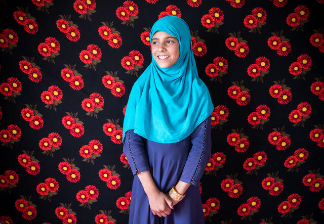 Bibi Asha standing in front of a flower-patterned background, looking to the side
