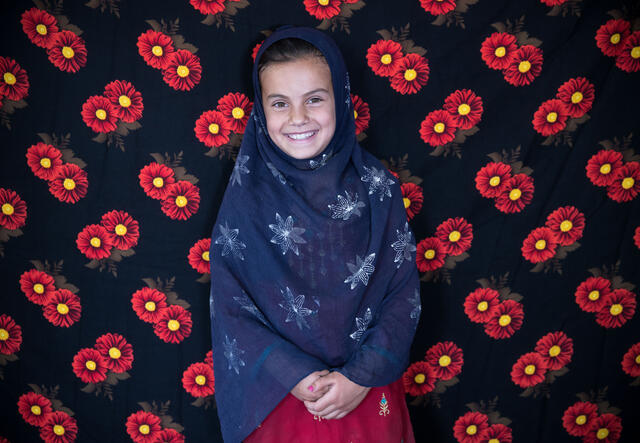 Zahra standing in front of a flower-patterned background, smiling at the camera