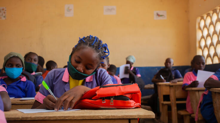 Kauvaumah writing in her notebook at her school