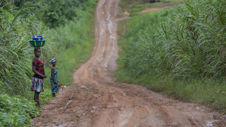 Two children walking down a dirt road.